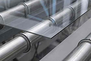  A close up of a sheet of glass on metal rollers
