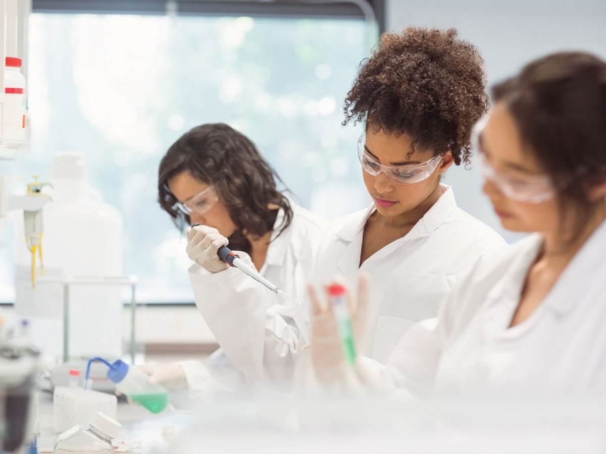 three women wearing safety glasses working in a lab