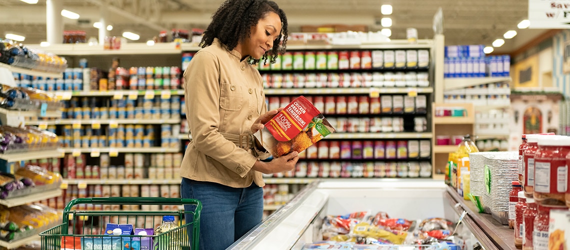 Woman in a grocery store buying a package of frozen chicken Woman in a grocery store buying a package of frozen chicken