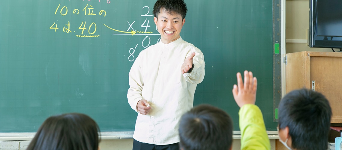A smiling teacher calls on one of his students