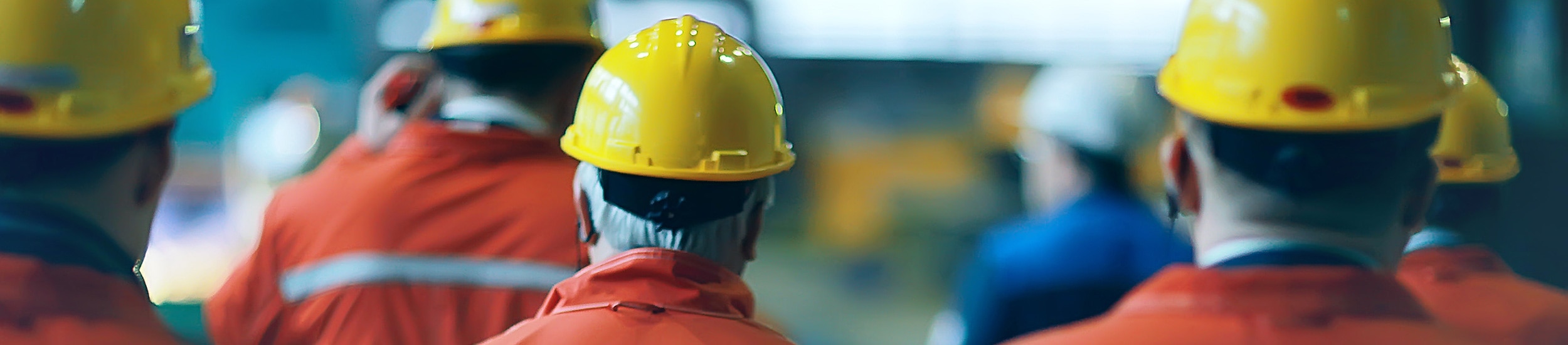 plant workers wearing PPE looking walking away from camera