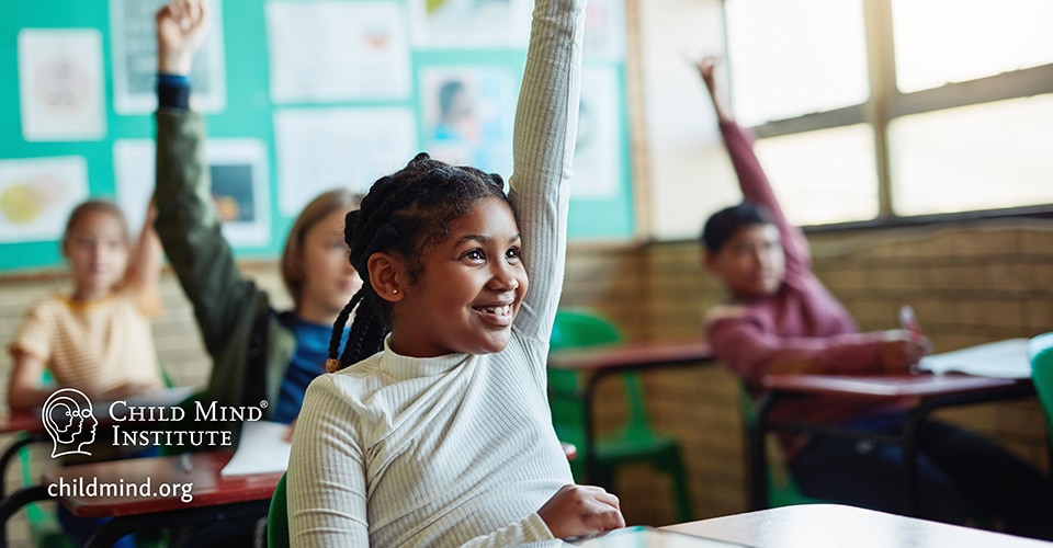 Children in classroom raising their hands