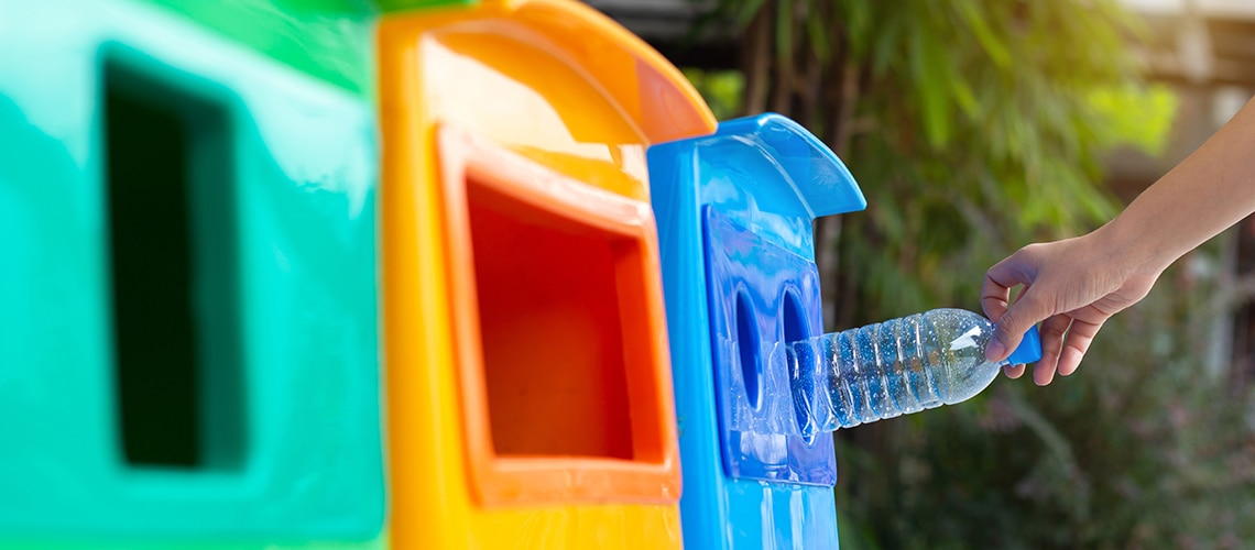 plastic bottle being placed into recycling container