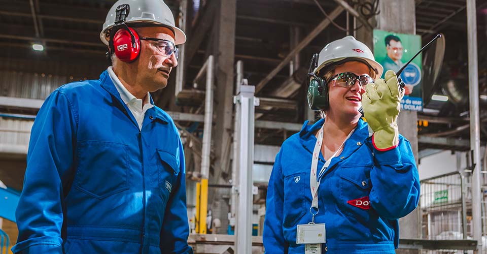 Two Dow colleagues in hard hats talk in a plant