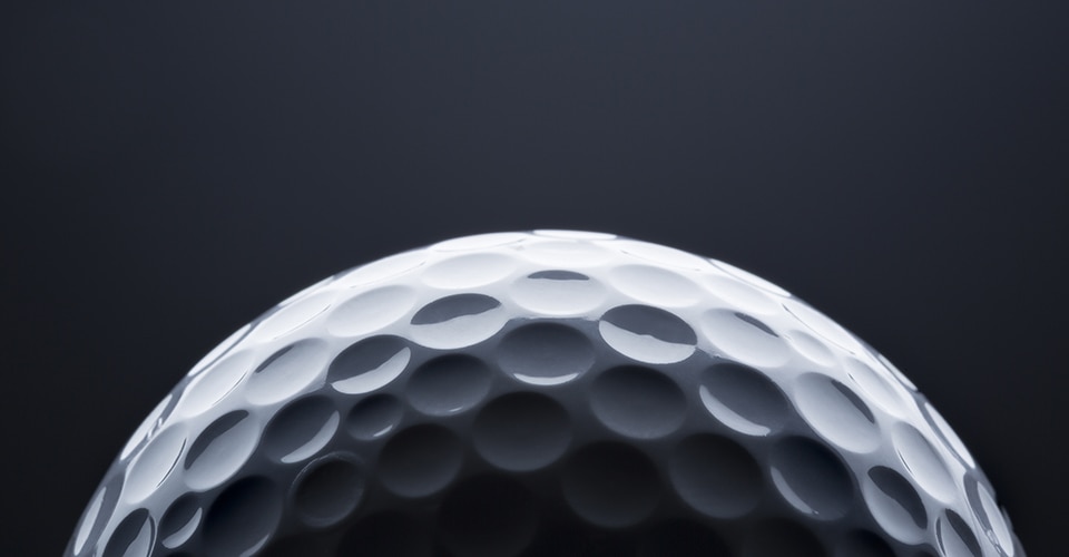 Top half of a golf ball against a dark background