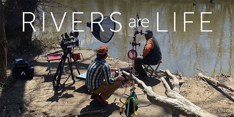 picture of videographers with camera set up alongside a river to film