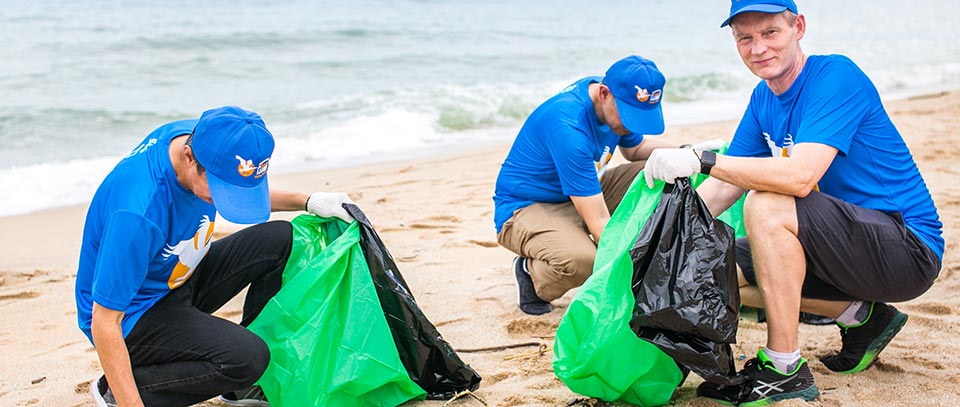 Volunteers picking up waste on the beach at a PullingOurWeight clean-up