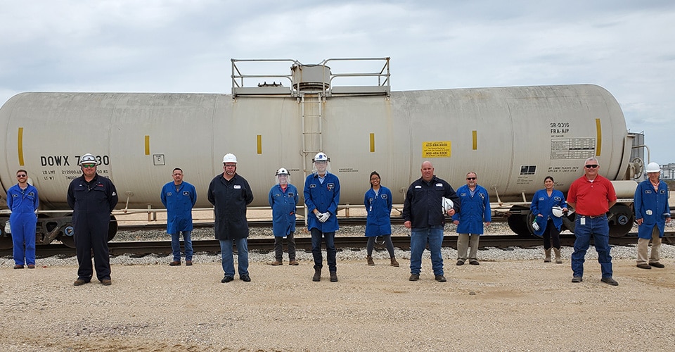 Dow employees at Texas City stand in front of a railcar of IPA
