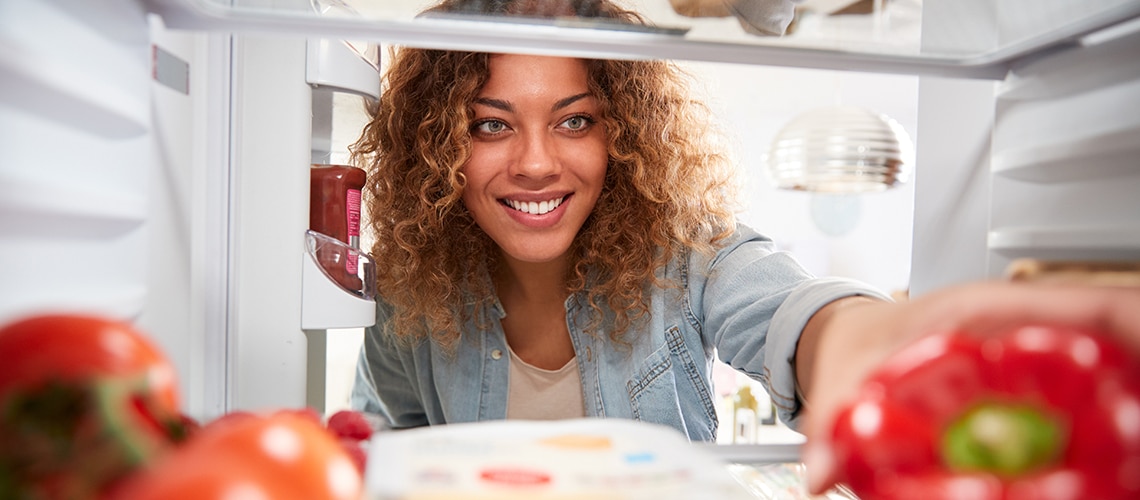 Woman reaching in to refrigerator for a healthy food option