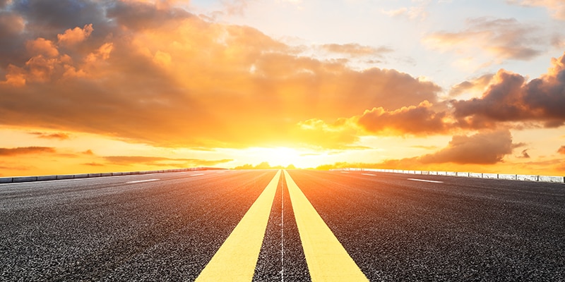 Road with yellow lines leading into a sunset