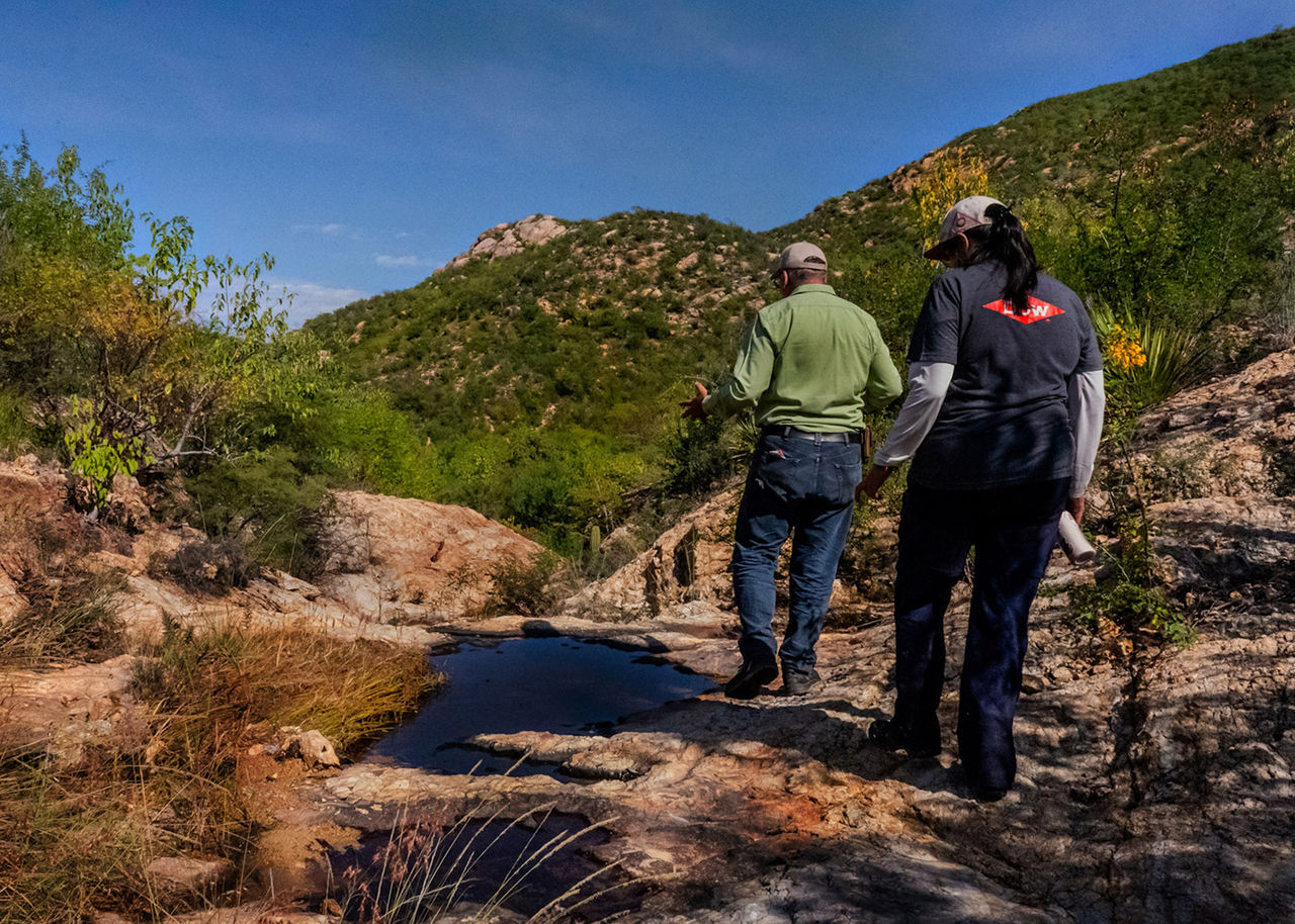 Man and a woman in a Dow t-shirt hike in a dry stream bed