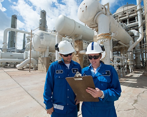 Two plant employees look at a clipboard