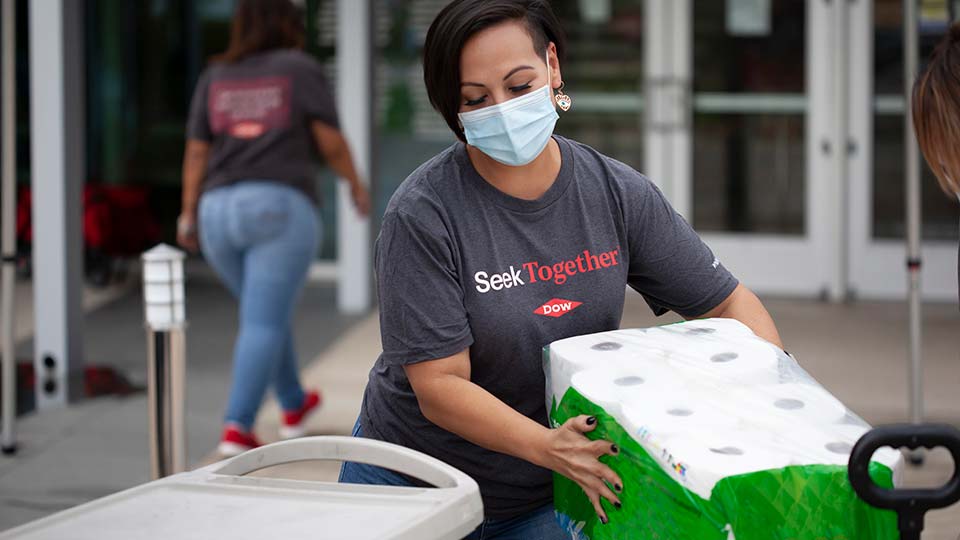 Dow volunteer wearing a mask carrying toilet paper