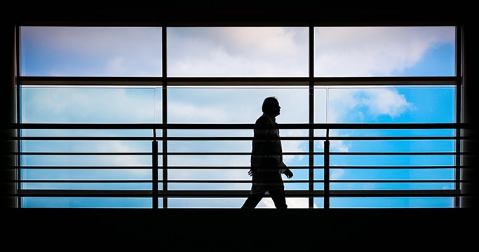 silhouette of person walking in front of large window 