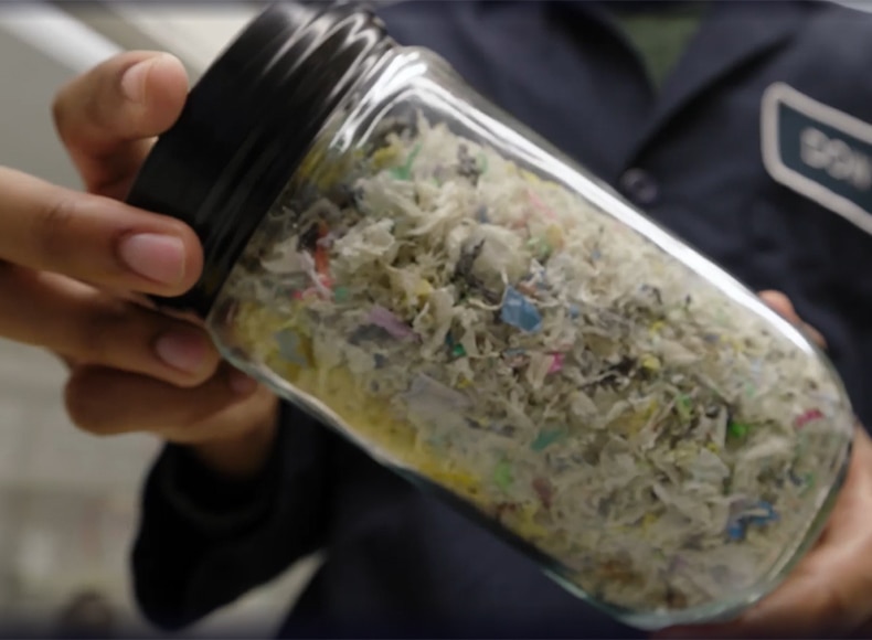 Dow scientist holding jar of recycled plastic material