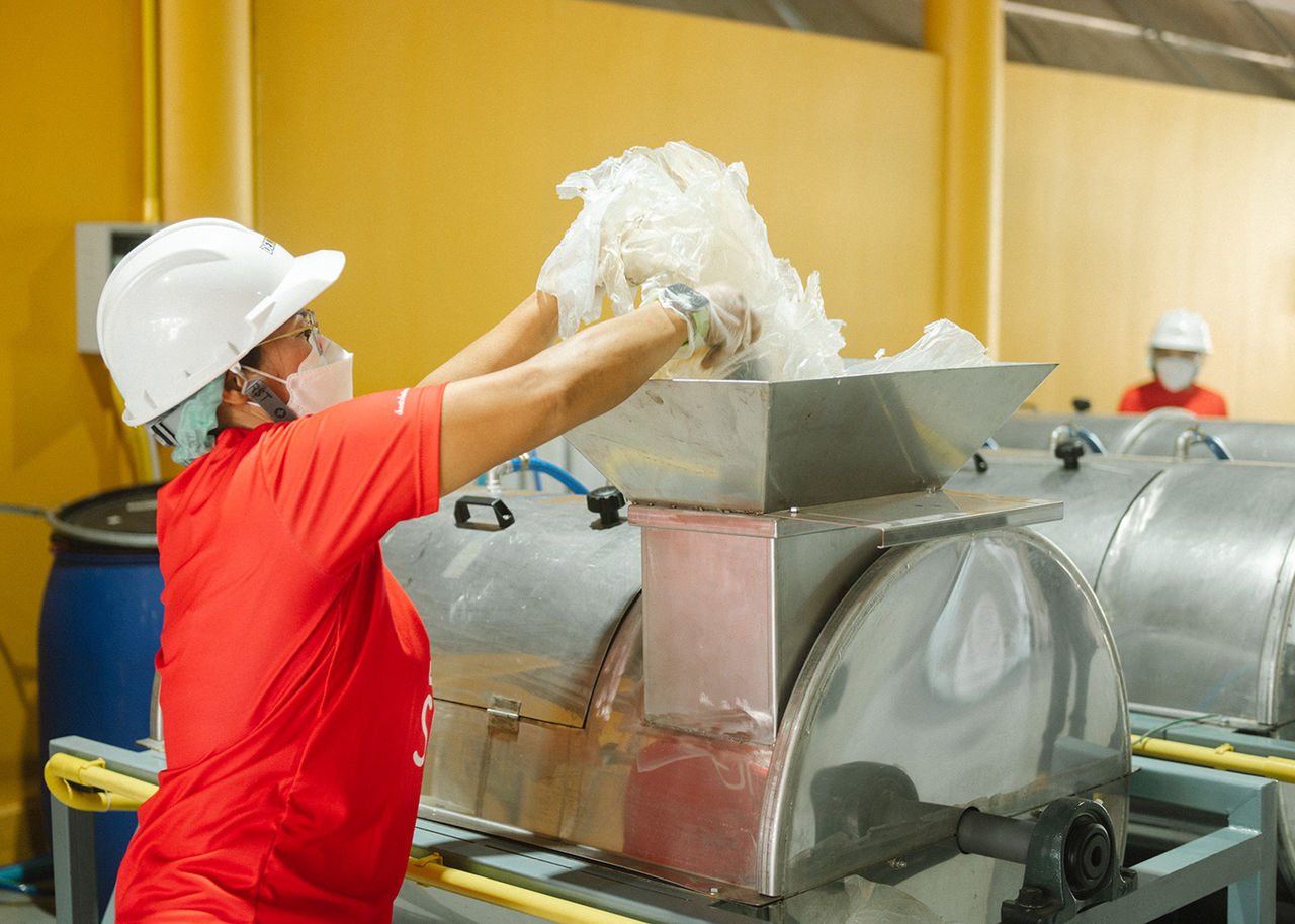a recycler loads plastic wrap into recycling equipment