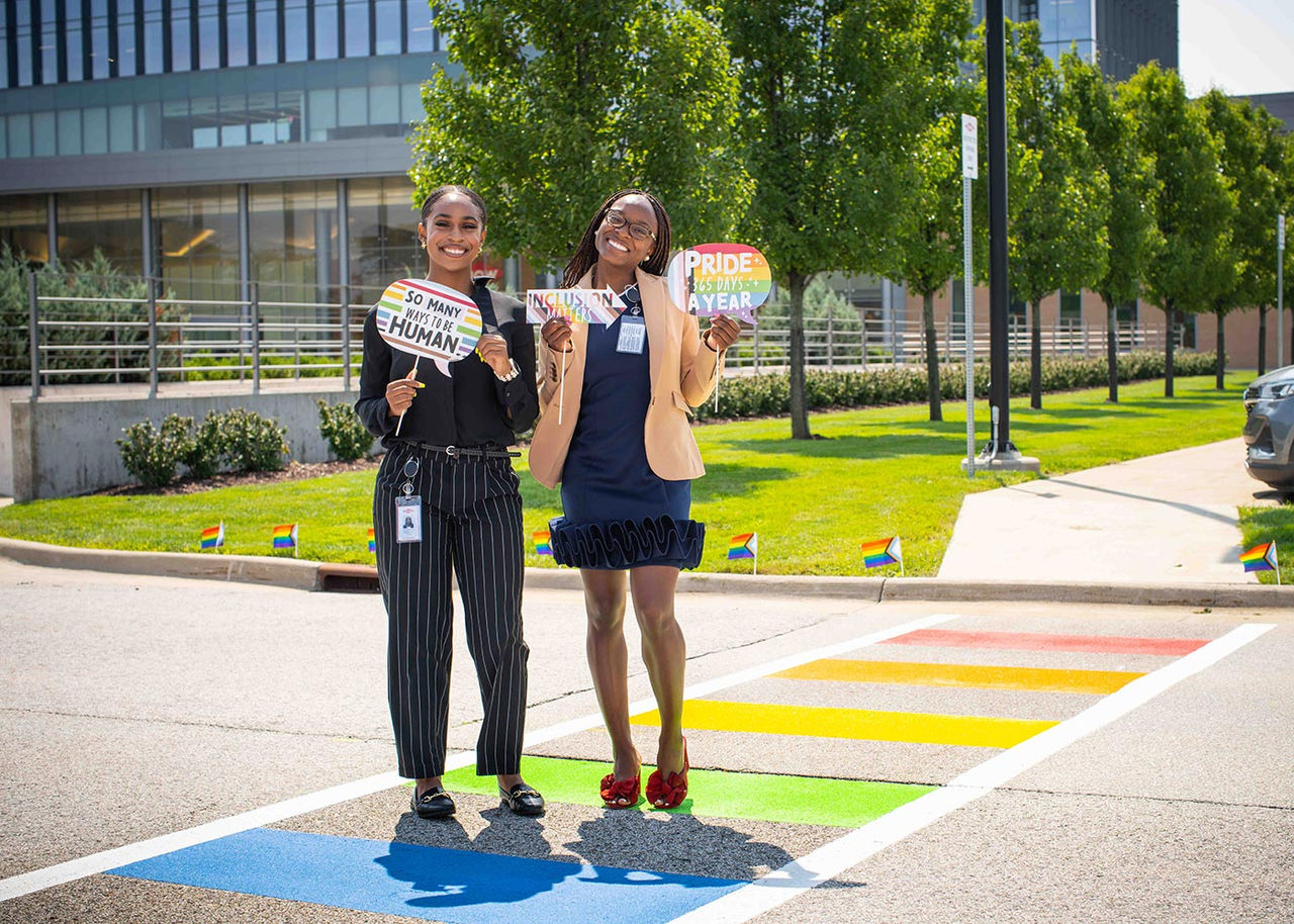 Two employees pose on the rainbow cross walk