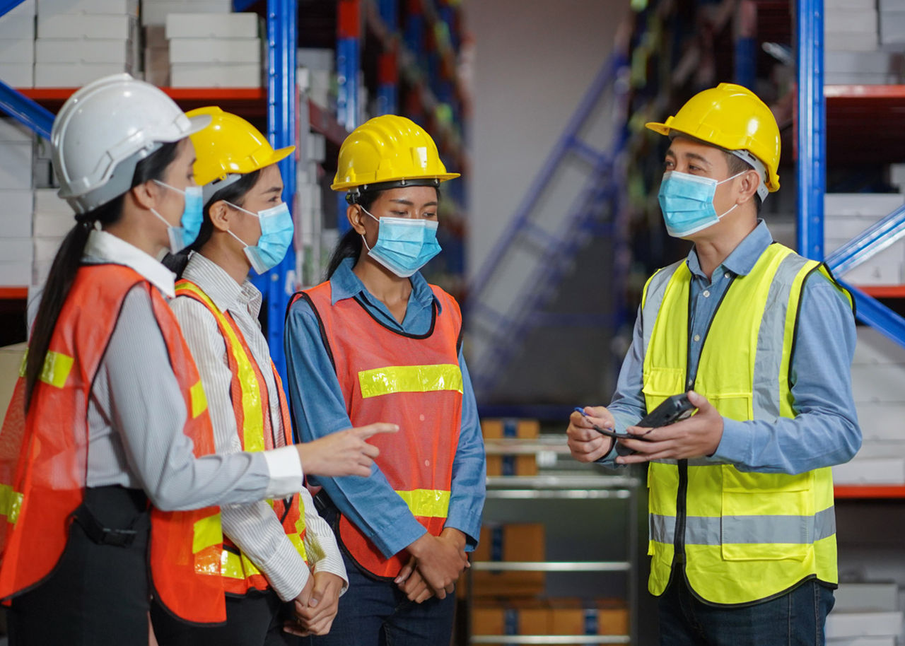 four workers talking in a warehouse