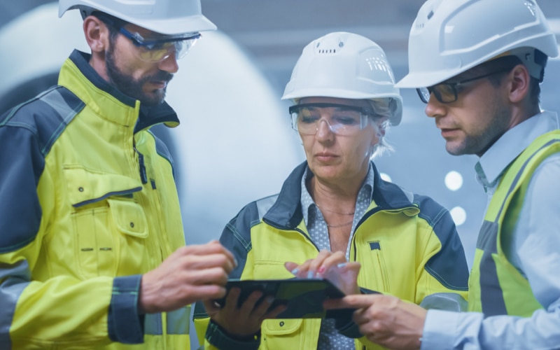 3 colleagues in PPE looking at tablet
