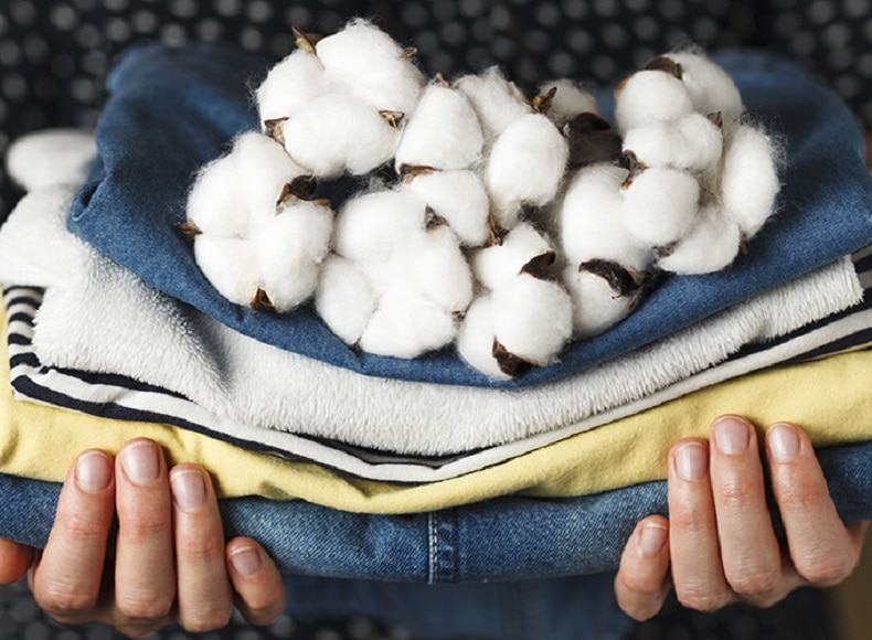 person holding cotton flower on top of folded clothing